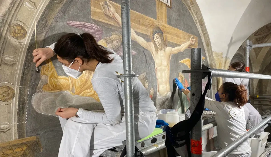 Art conservators restoring a religious fresco depicting the crucifixion of Jesus.